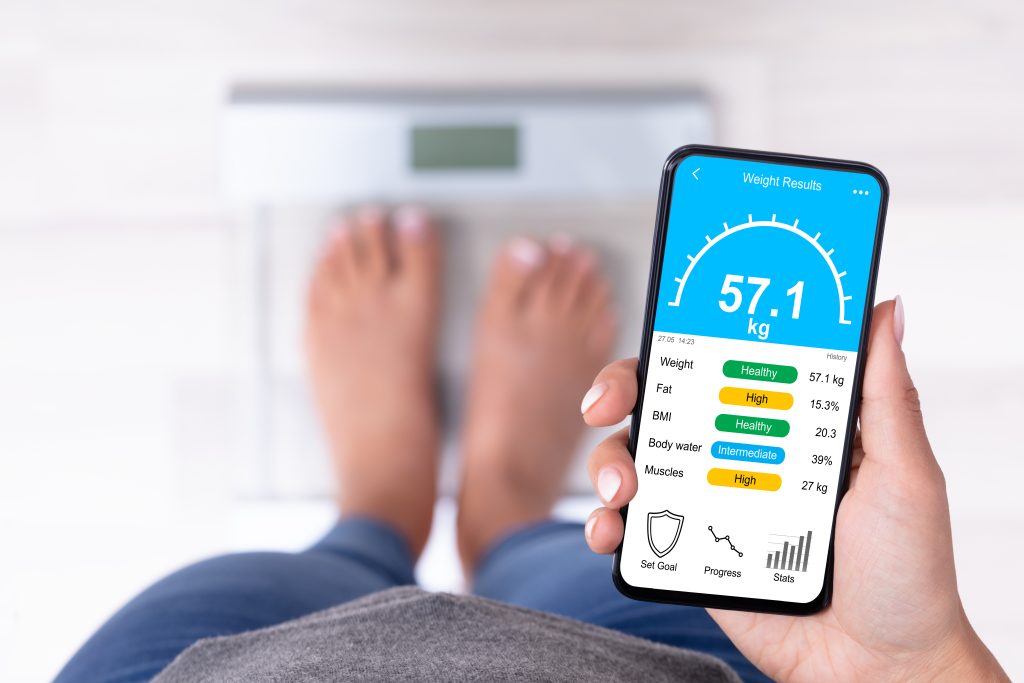 Woman standing on smart scale looking at app on her phone